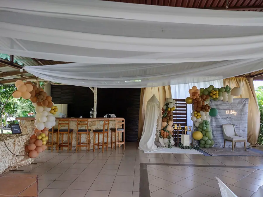 Rancho Bambú montado para un baby shower con cortinas blancas y arcos de globos